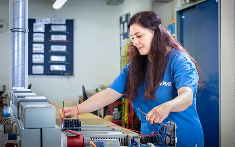 Teilnehmerin der Umschulung zur Industrieelektrikerin für Betriebstechnik führt Messungen und Spannungsprüfungen an elektrischen Anlagen in der Elektroausbildungswerkstatt durch.