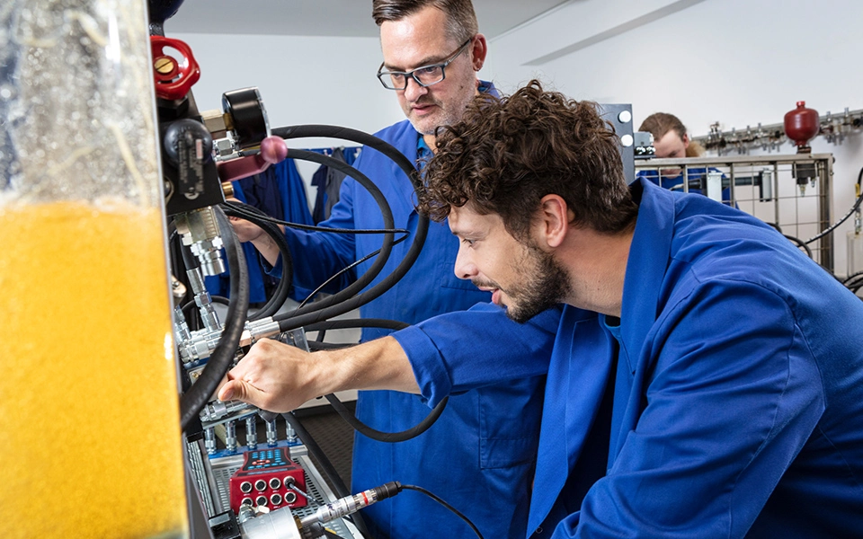 Ausbilder und Teilnehmer an Hydraulikstand