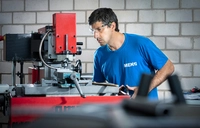 Teilnehmer der Umschulung zur Fachkraft für Metalltechnik – Zerspanungstechnik arbeitet an einer konventionellen Fräsmaschine in MEK-Arbeitskleidung.